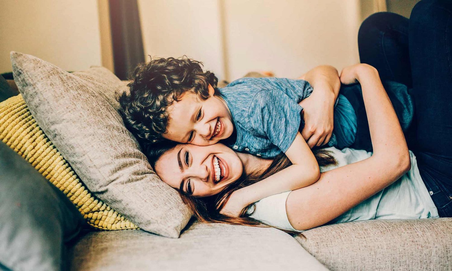 A young child is hugging an adult, possibly a parent, in a cozy indoor setting.