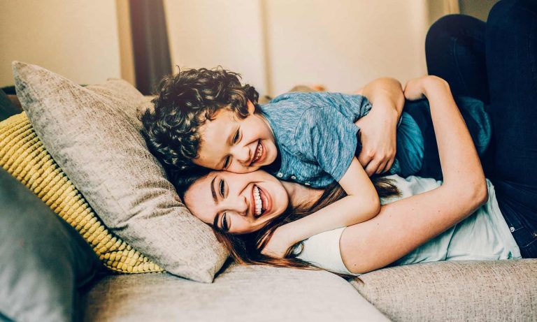 A young child is hugging an adult, possibly a parent, in a cozy indoor setting.