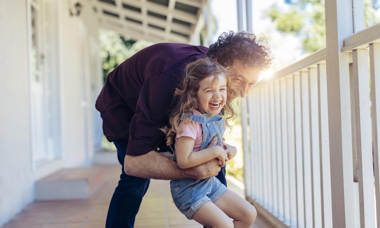 Person holding child in front of house.