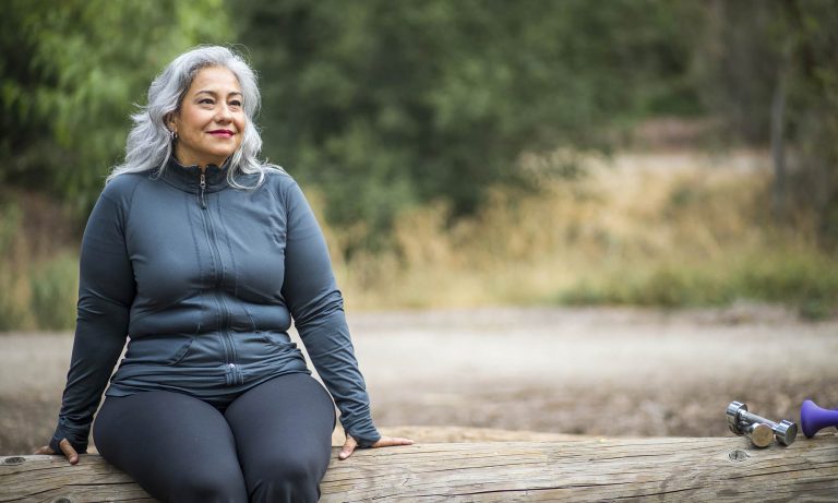 Woman sitting on a bench, smiling.