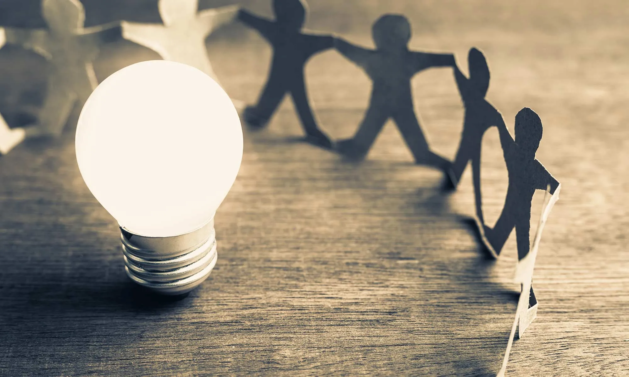 A lightbulb with silhouettes of people gathered around it.