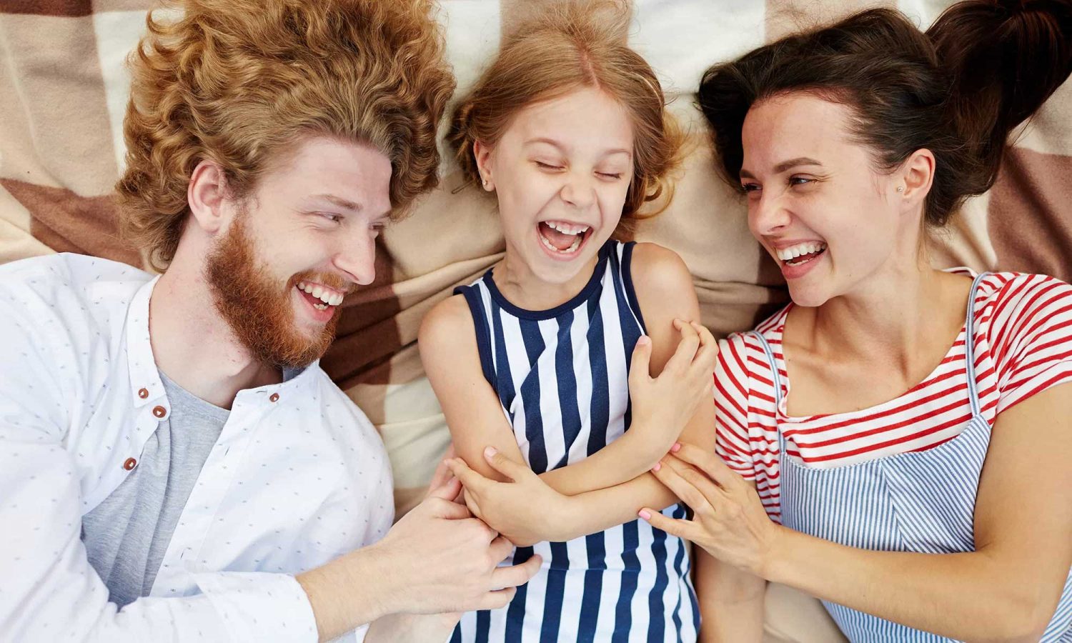 Family of four posing together on a bed.