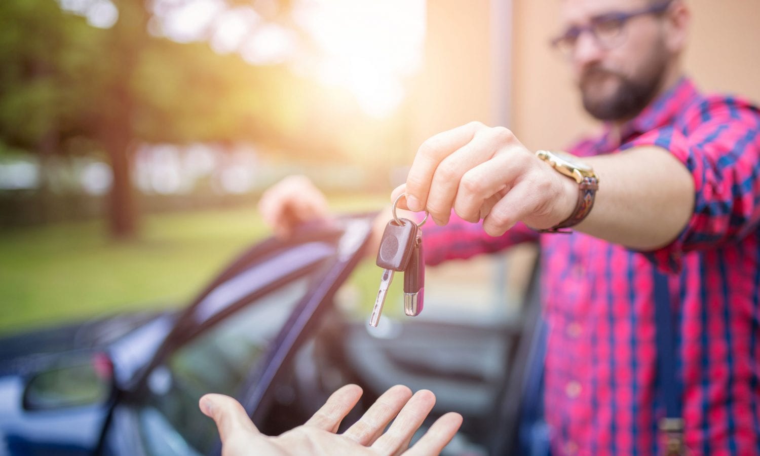 A man hands car keys over to an outstretched hand.