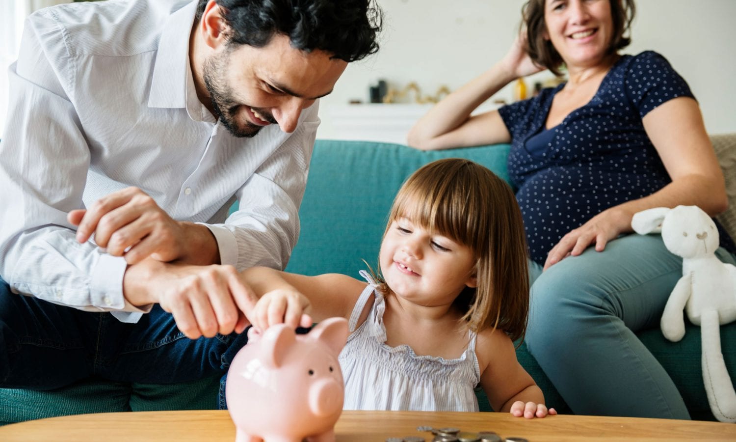 Father shows his daughter how to save money with a piggy bank.