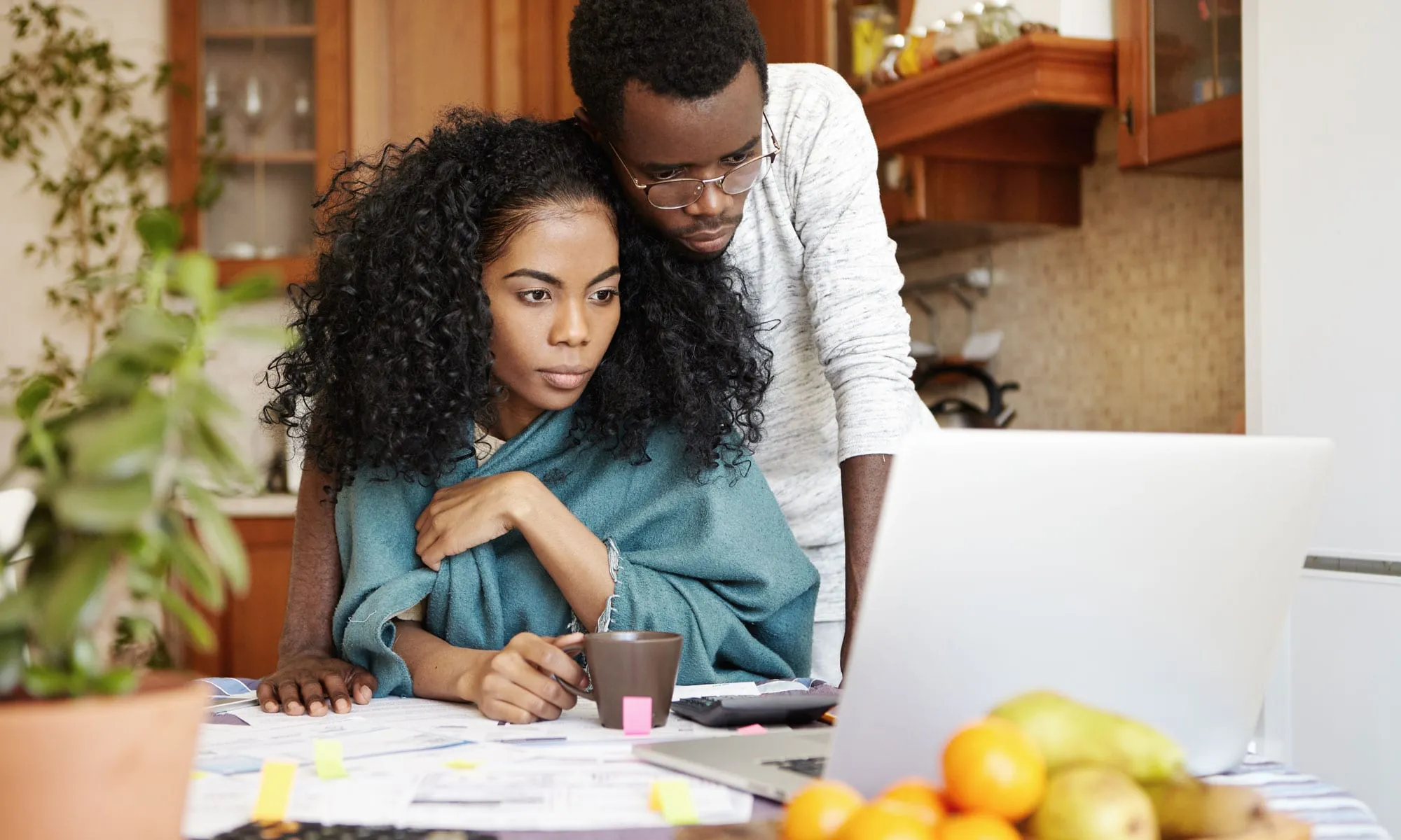 A man and woman sitting at a desk with a laptop.