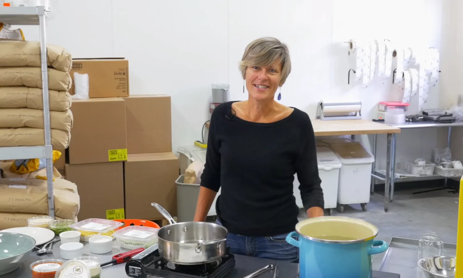 A woman standing behind a counter full of kitchen supplies.