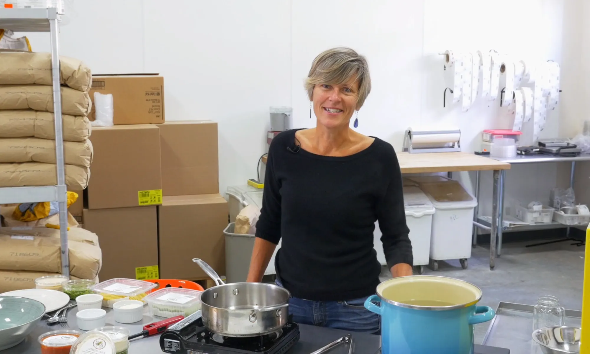 A woman standing behind a counter full of kitchen supplies.