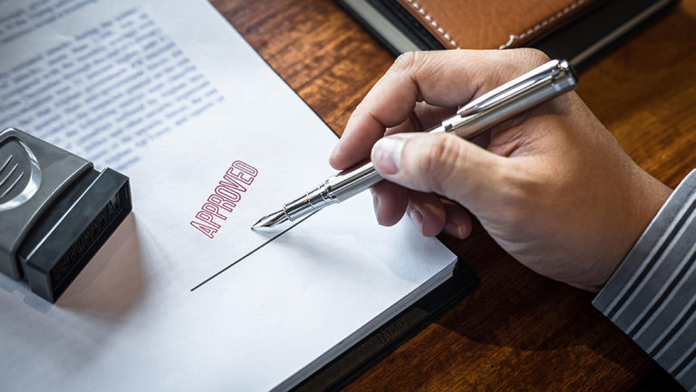 Signing a document at a desk.