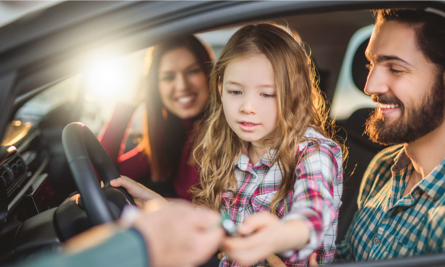 A family in a car with the father driving, the mother seated and a child on the driver's side.
