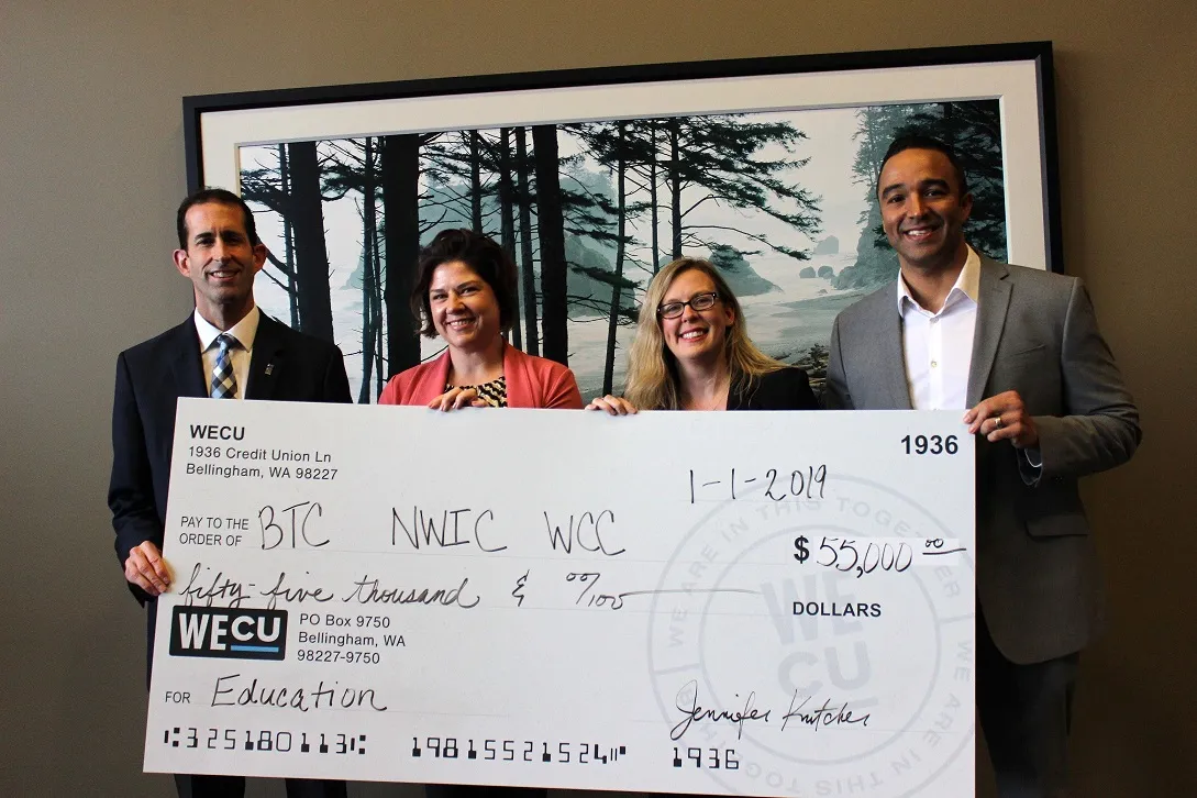 The image features a check presentation in an office setting.