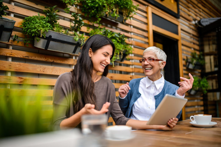 Two women sitting together at a cafe table.
