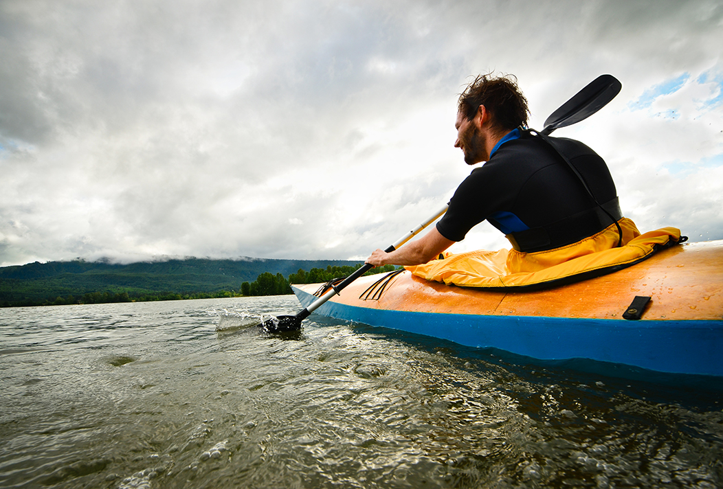 Kayaker on river, paddling and looking back.