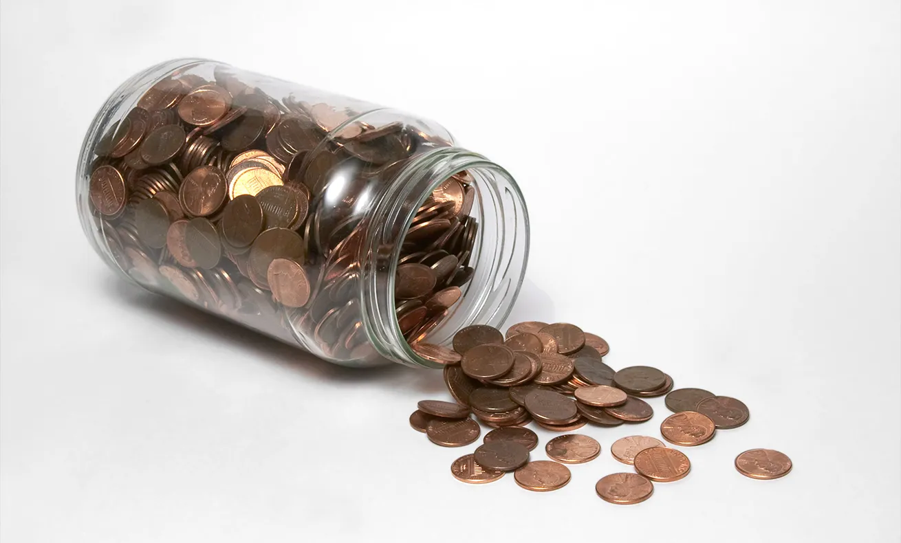 A jar full of coins and money on a table.