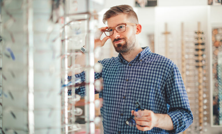 Man wearing glasses, standing in front of display shelves.