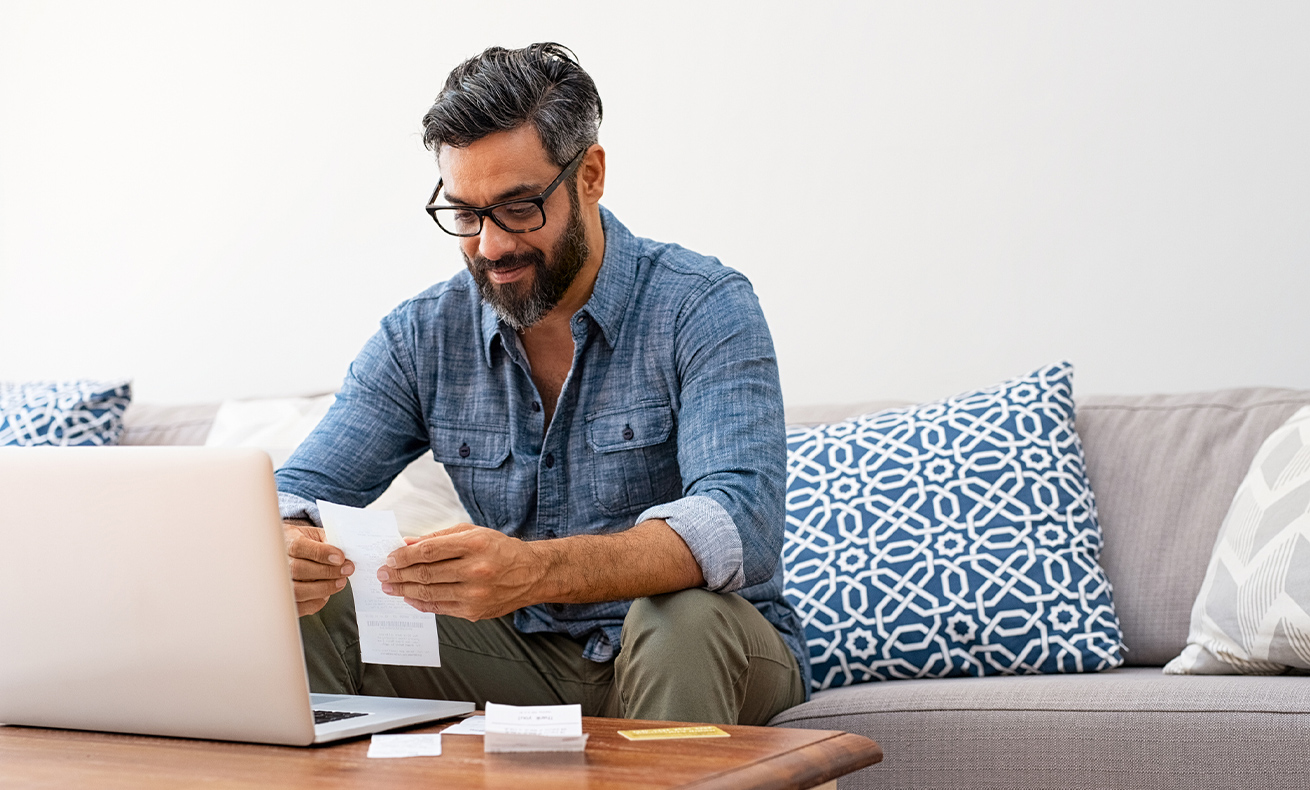 Man sitting on couch working on laptop.
