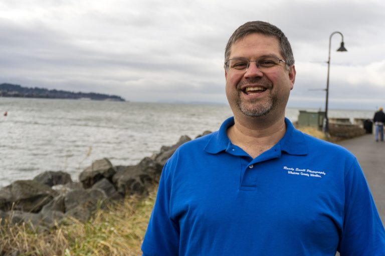A man posing for a photo near the sea.