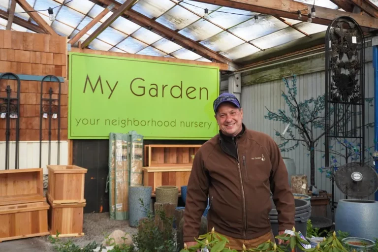 A man standing in front of a sign advertising a nursery