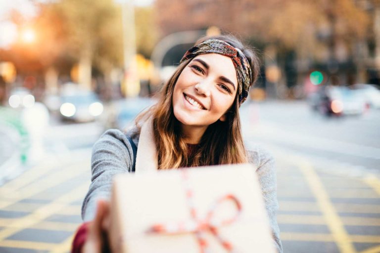 Woman holding gift box on street