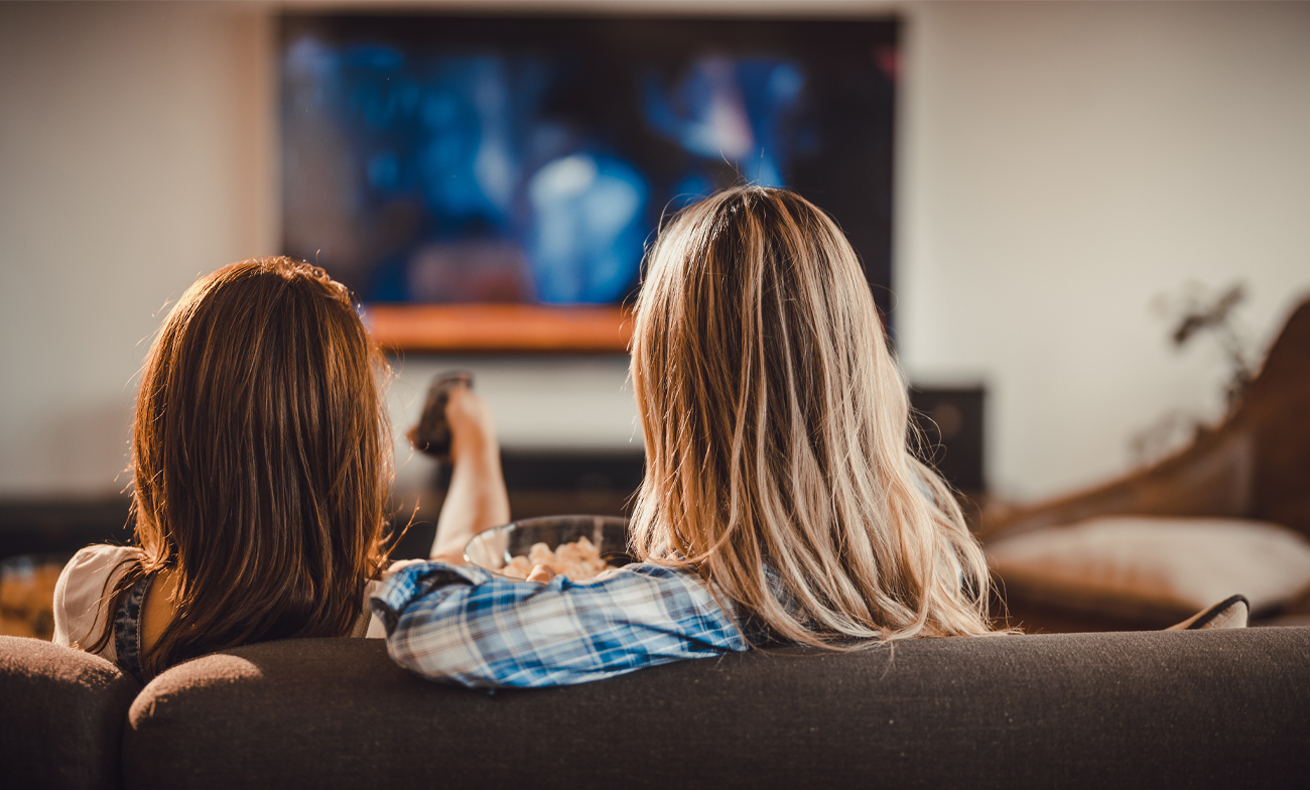 Two people sitting on a couch in a living room.