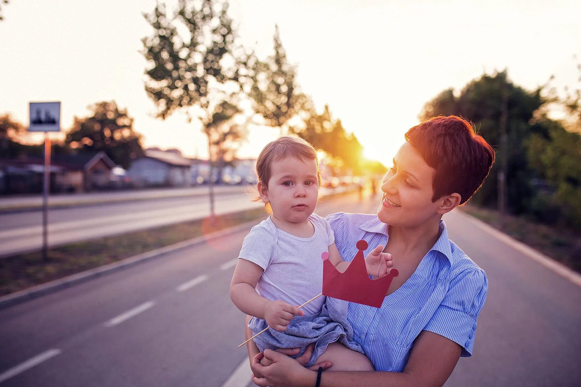 A smiling woman holding a baby while posing in front of a sunset
