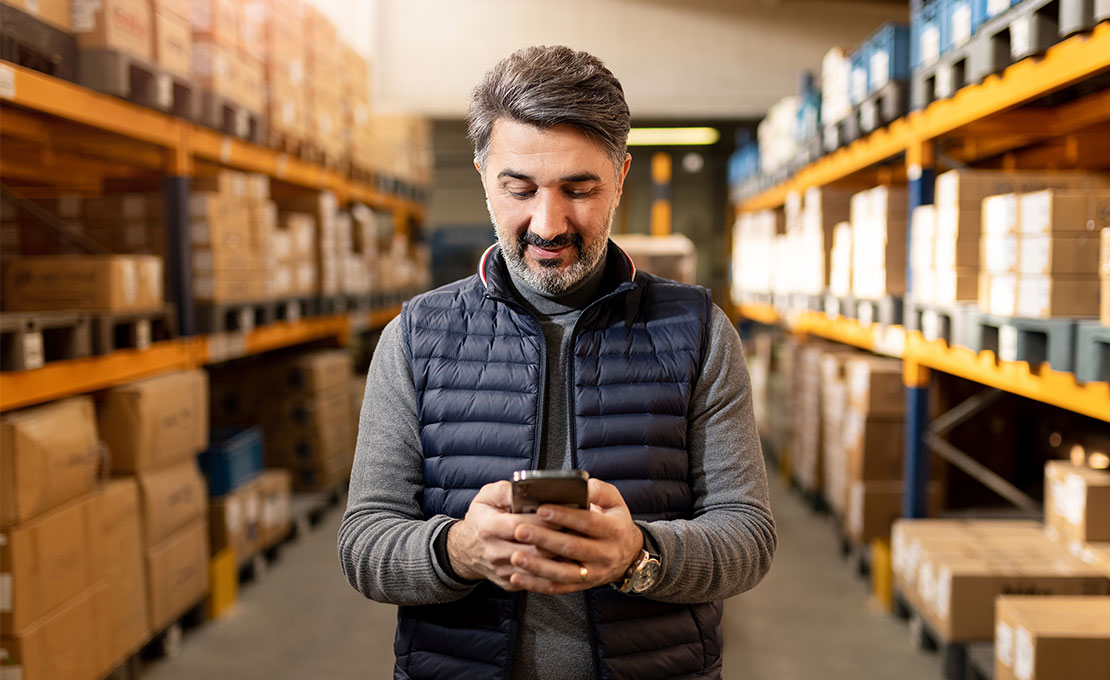 Man looking at phone in an aisle of boxes