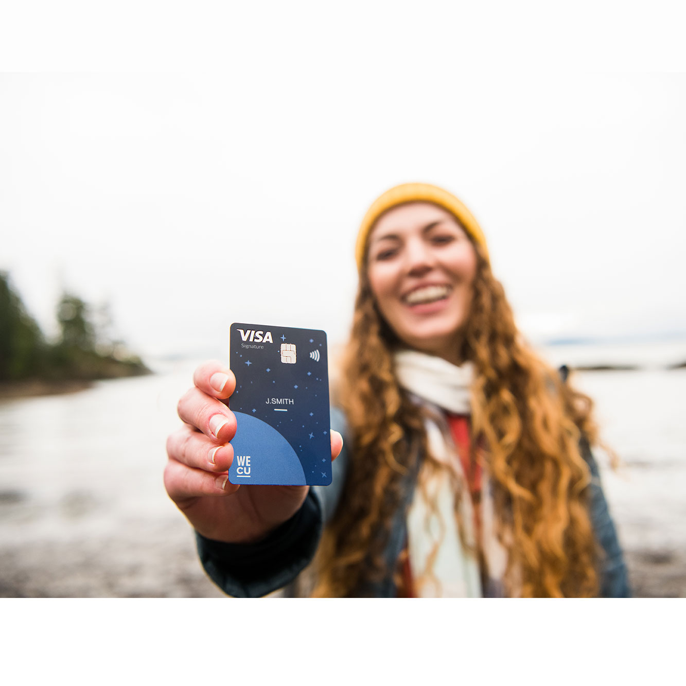 A woman holding up a WECU credit card