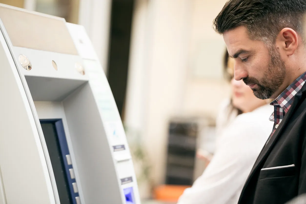 An ATM machine with a person standing in front of it.
