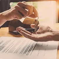 One pair of hands drops keys into another for a new commercial real estate purchase.