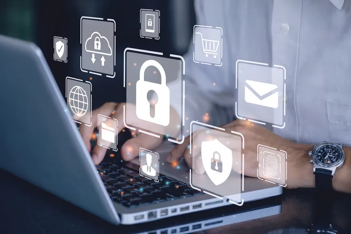 A person working on a laptop with security-themed digital icons.