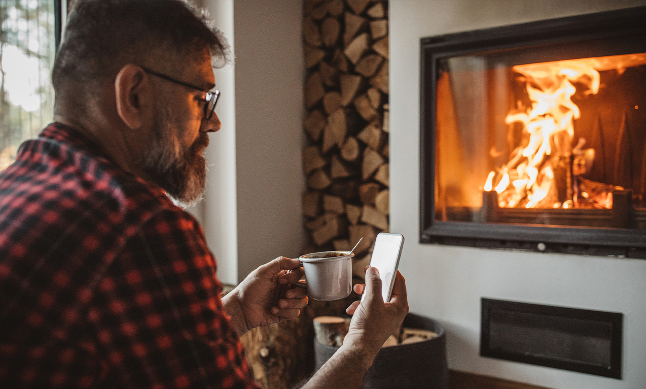 Man sitting in front of a lit fireplace.