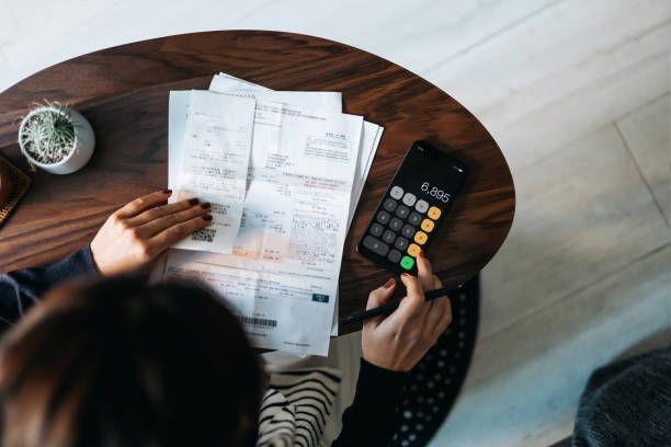 Person working on paperwork with pen and phone in hand.