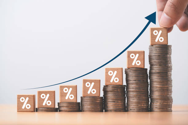 An illustration depicting a hand holding a stack of coins while a graph with boxes and dollar signs grows upward, indicating financial growth or prosperity.