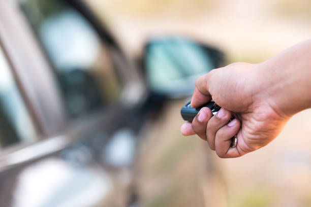 Hand holding car key near car door.