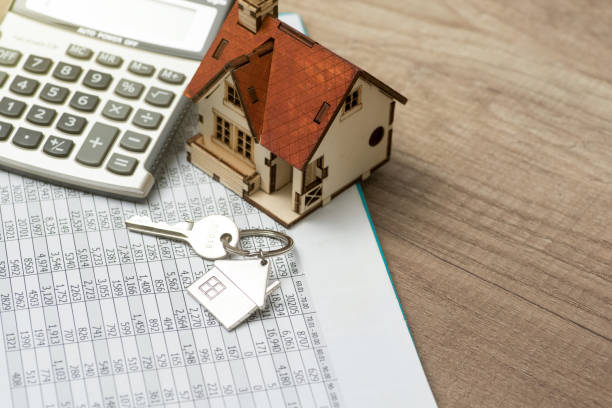 Calculator, house model and keys on top of spreadsheet.