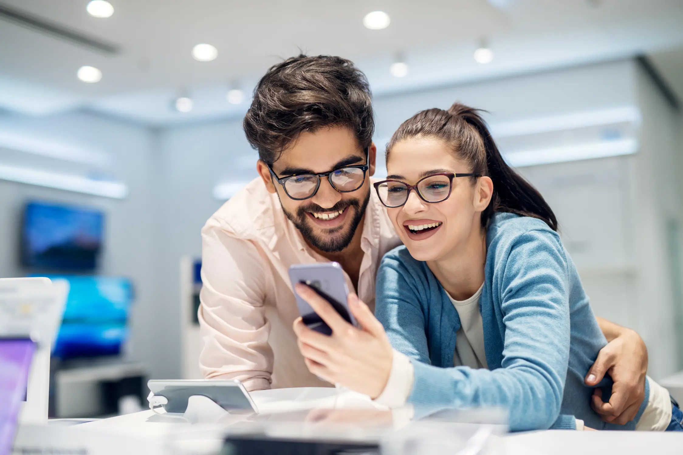 Two people smiling at a smartphone.