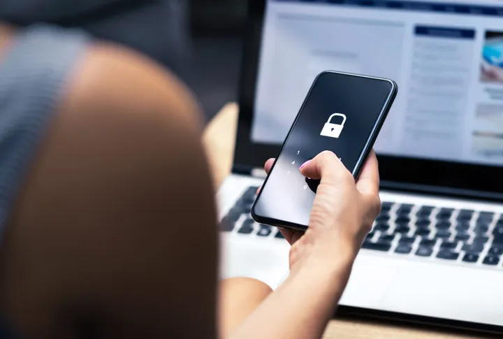 Hand holding a smartphone with a lock icon on the screen, viewed from above.