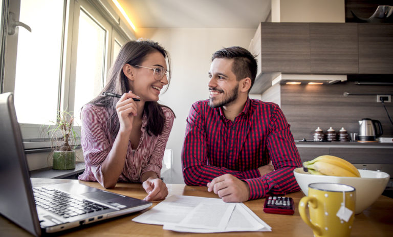 Two people sitting at a table in front of a laptop.