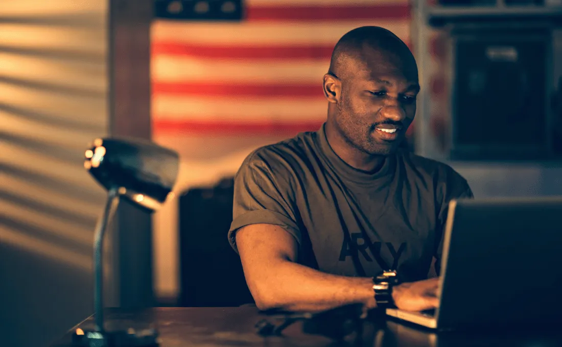 Man in army shirt working on laptop.