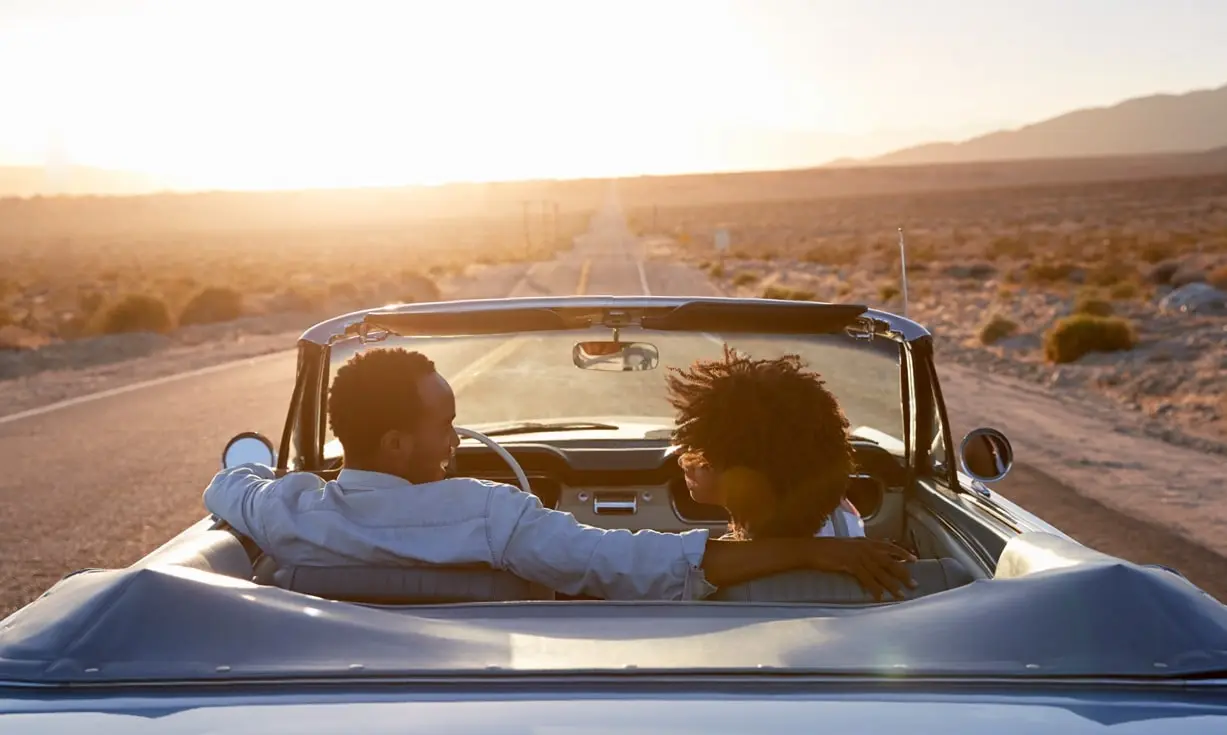 Man and woman riding in a car at sunset