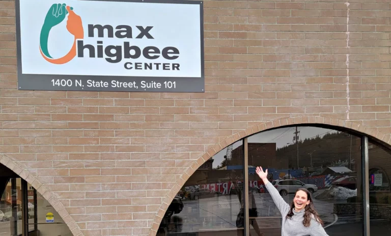 A woman taking a selfie in front of a sign for Max Higbee Center.