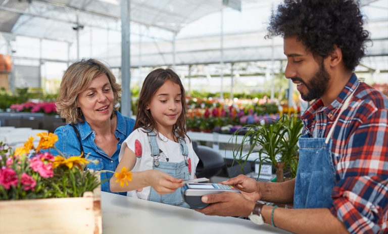 Three people standing at a flower stand.