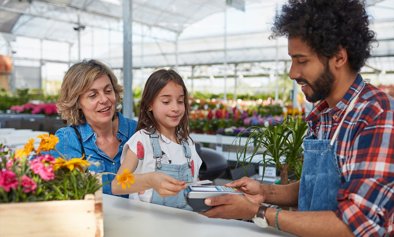 Three people standing at a flower stand.