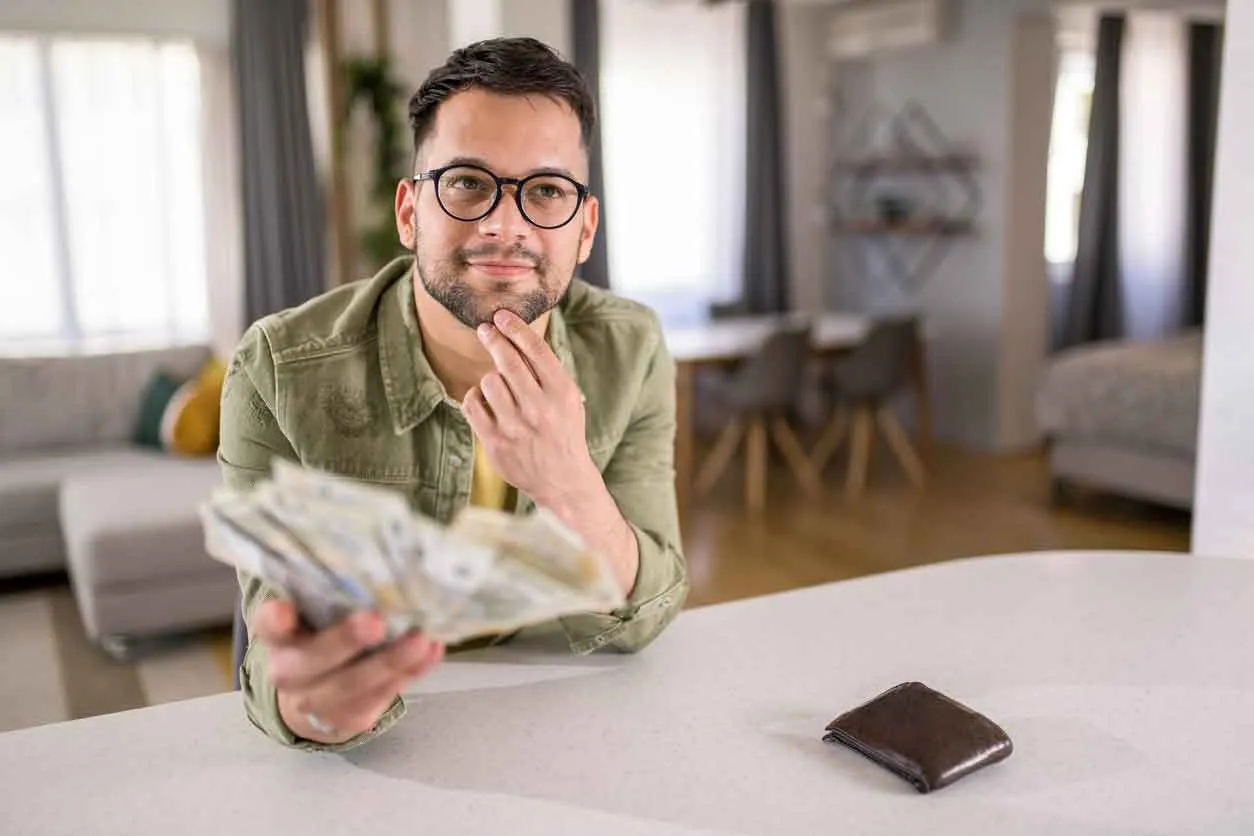 Man holding money with thoughtful expression.