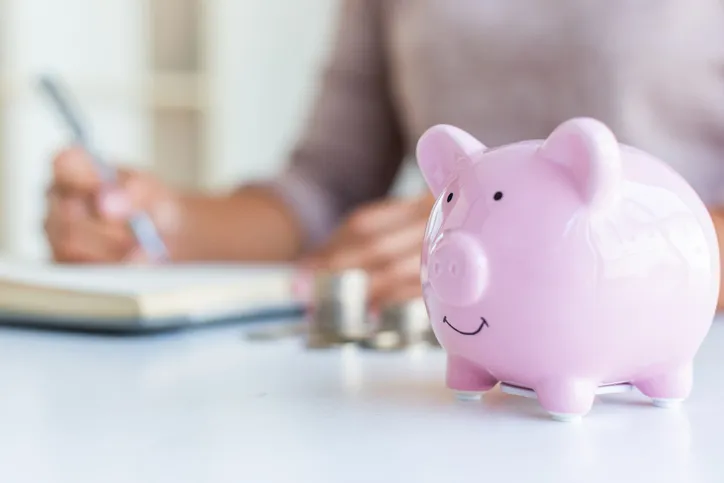 Pink piggy bank sitting on desk.