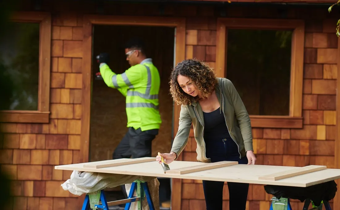 A woman in a construction setting, working on a wooden structure.