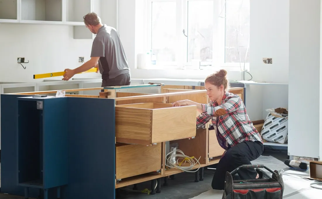 A couple working on a kitchen cabinet installation.
